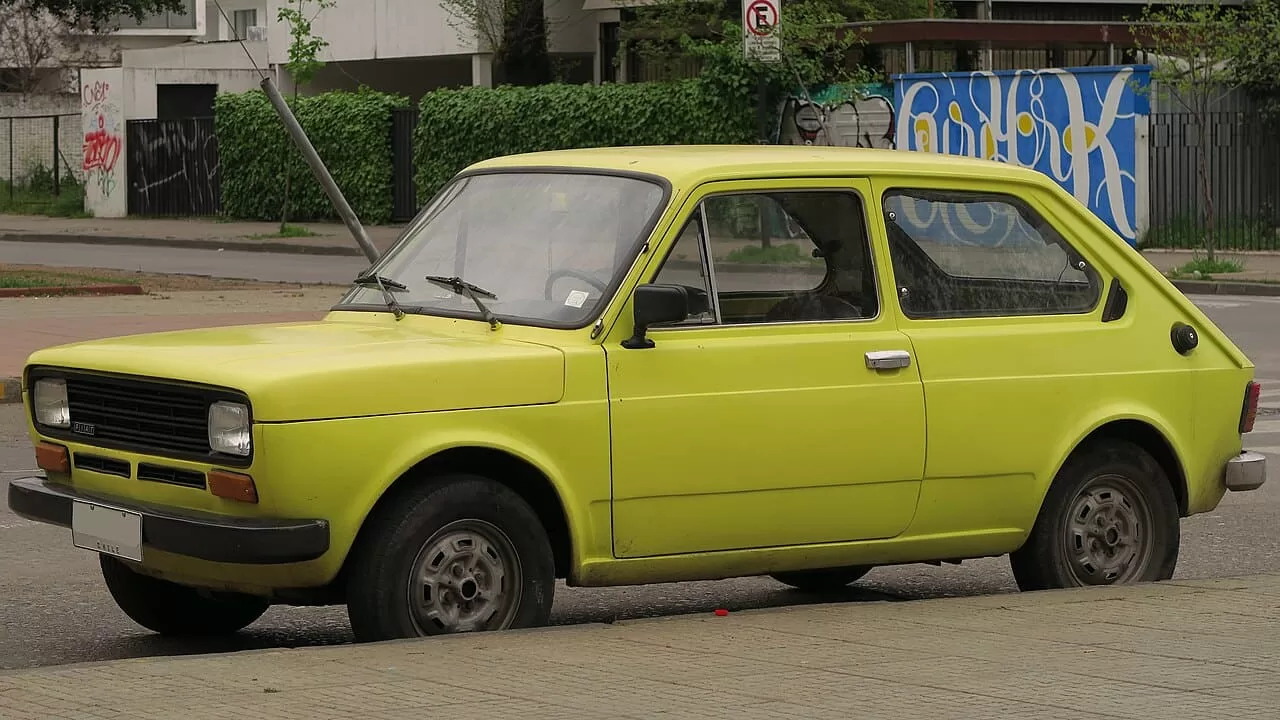 Fiat 147 amarelo no centro urbano, representando eficiência e inovação.