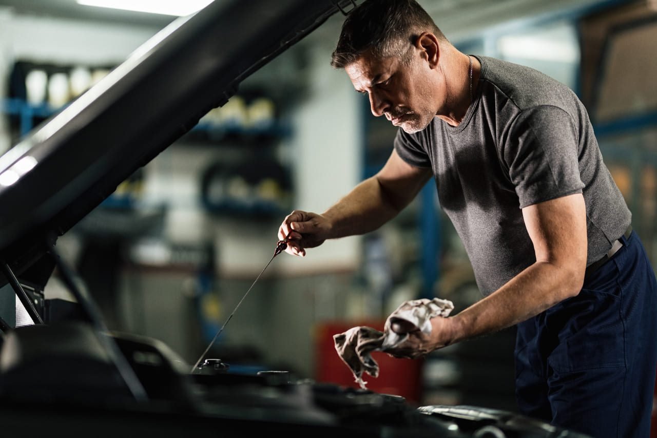4. Troca de óleo do motor: Mecânico checando o óleo de um motor antes do processo de troca.