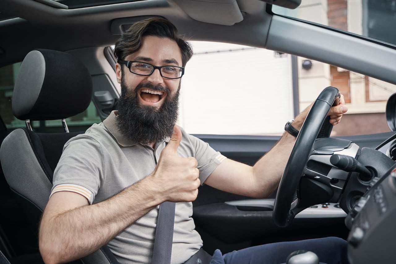 Motorista sorrindo dentro do carro: Motorista satisfeito no interior de seu veículo, simbolizando a eficiência e desempenho do motor após manutenção adequada.