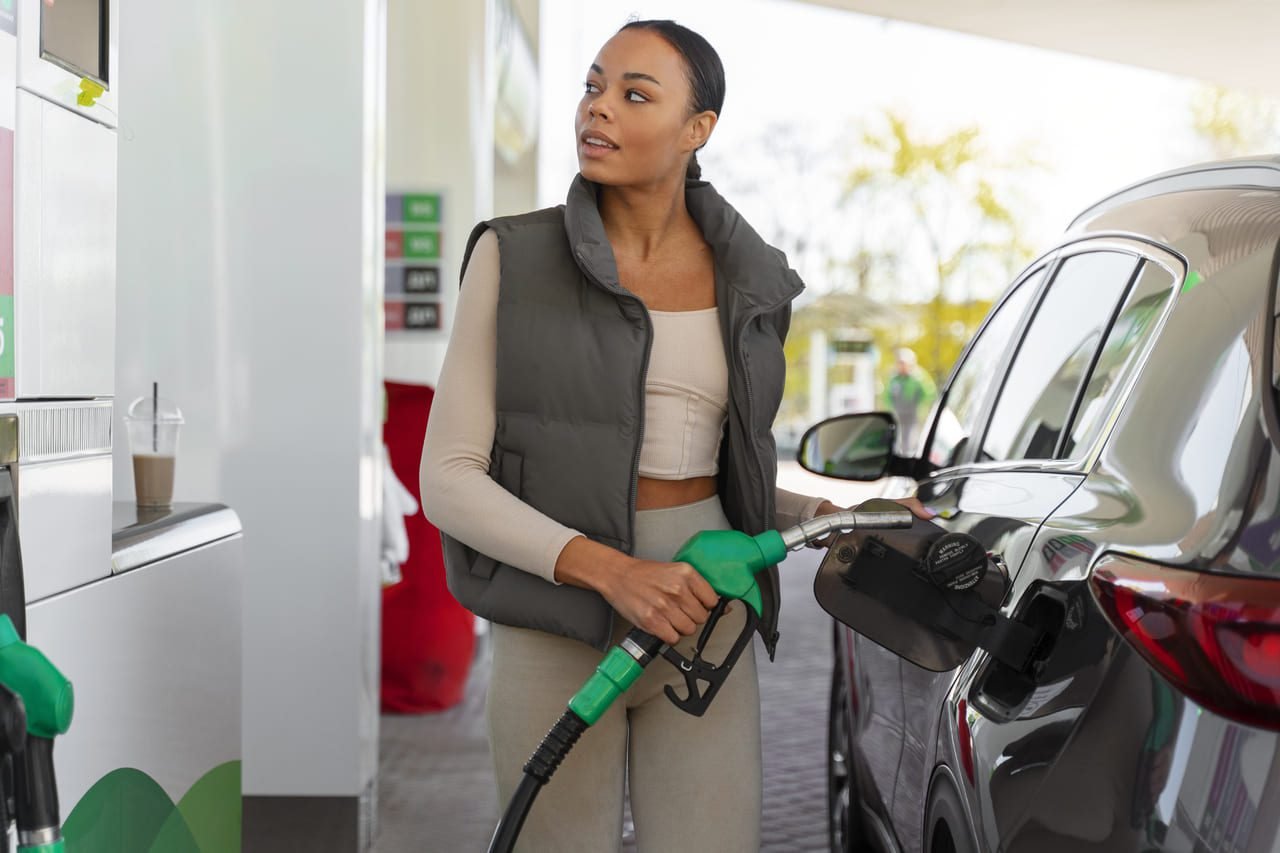 Mulher com carro posto de gasolina: Reabastecimento de combustível em veículo alugado, destacando a importância do retorno com tanque cheio.