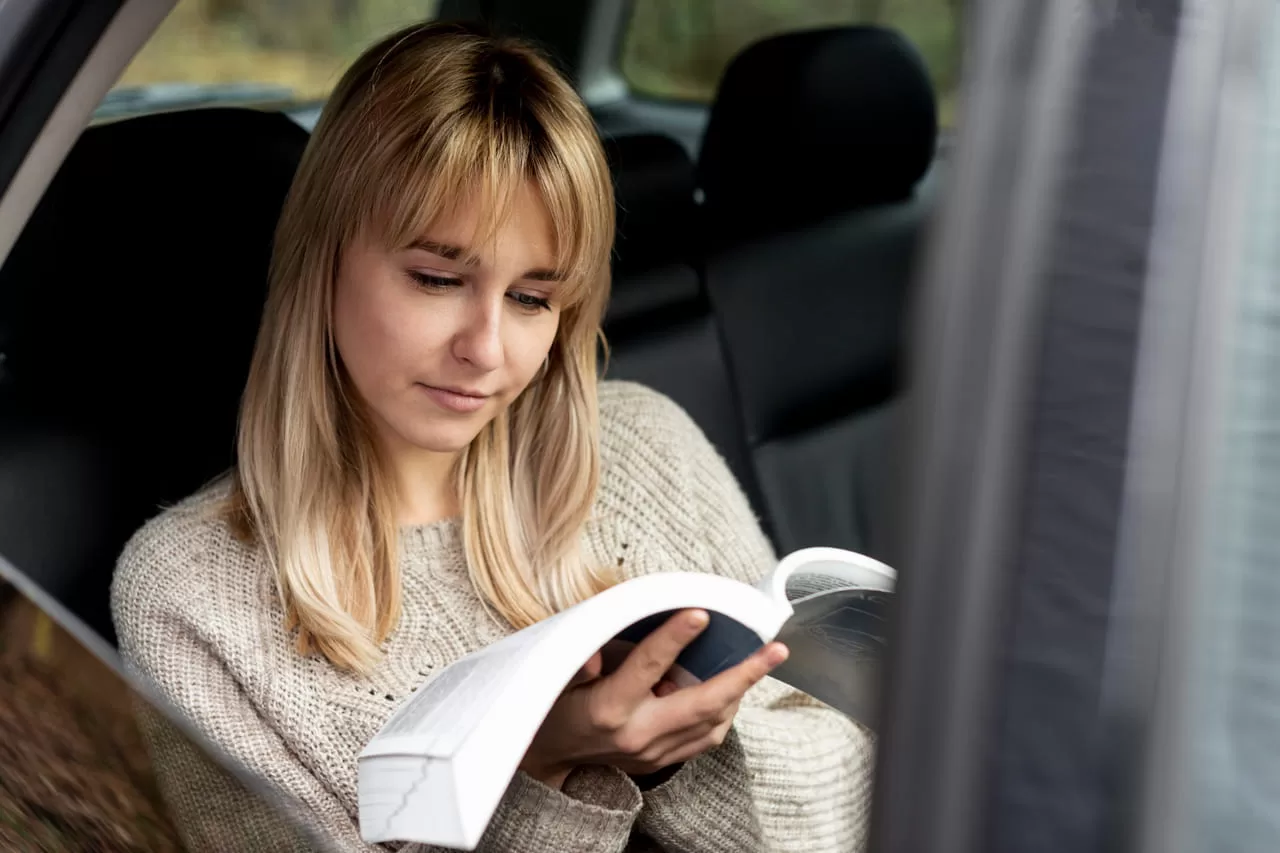 Mulher com um manual do veículo aberto, mostrando como é um recurso valioso.