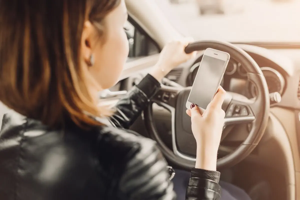 Mulher de sentada no carro usando seu smartphone